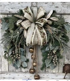 a christmas wreath hanging on the side of a wooden door with bells and greenery