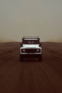 a white truck driving down a dirt road in the middle of an empty desert area