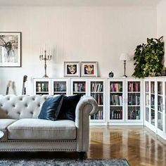 a living room filled with furniture and bookshelves next to a wall covered in pictures