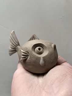 a hand holding a clay sculpture of a fish