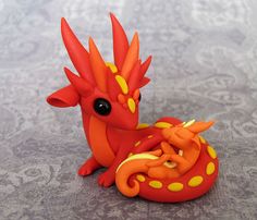 an orange and yellow dragon figurine sitting on top of a gray tablecloth