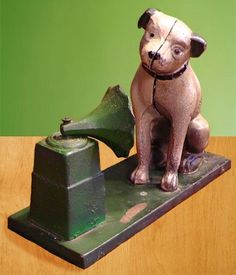 a dog figurine sitting on top of a green and brown table next to a bell