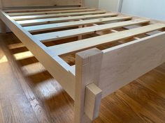 a wooden bed frame sitting on top of a hard wood floor