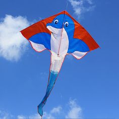 a blue and red kite flying in the air with clouds behind it on a sunny day