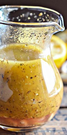 a glass pitcher filled with liquid sitting on top of a table next to sliced lemons