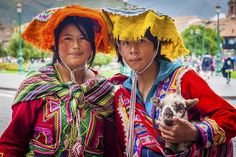 two women in colorful costumes holding a small animal