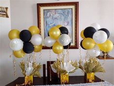 balloons and streamers are in vases on a table with gold, white and black decorations