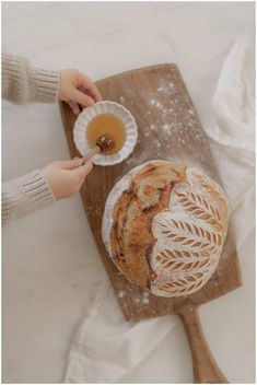 a person holding a bowl with some food in it on top of a wooden cutting board