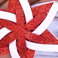 red and white glittered star ornament being held by someone's hand