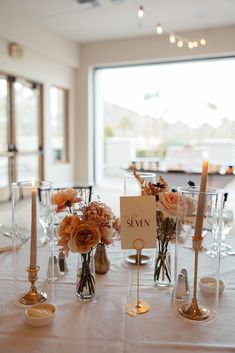 there are many vases with flowers and candles on the table at this wedding reception