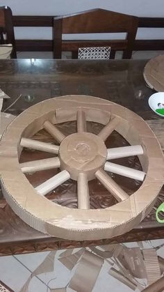 a wooden wheel sitting on top of a table next to some scissors and paper plates