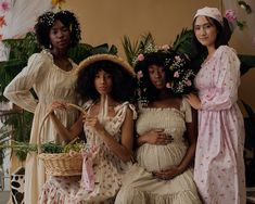 three women in dresses and bonnets posing for a photo with flowers on their heads