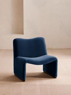 a blue chair sitting on top of a hard wood floor next to a white wall