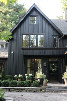 a black house with lots of windows and potted plants on the front steps in front of it