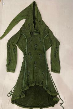 an old green dress is laying on a white cloth covered tablecloth, with the hood pulled back