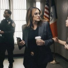 a woman standing next to a man holding a cup in front of an american flag