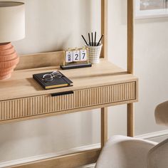 a desk with a clock, pen holder and other items on it in front of a chair