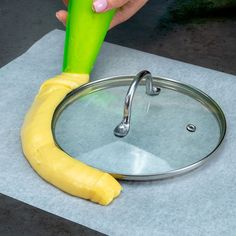 a person holding a green object over a pan with a banana on top of it