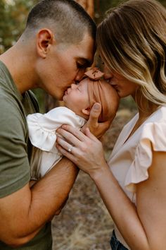 a man and woman kissing each other in front of the camera with trees behind them