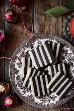 black and white striped cookies sitting on top of a plate next to christmas ornaments,