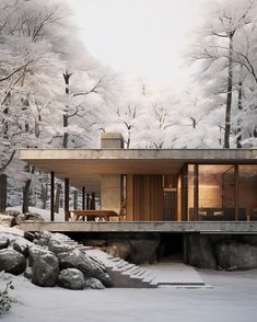 a house in the woods with snow on the ground and trees around it, surrounded by rocks