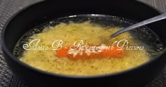 a black bowl filled with soup and a carrot