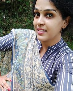 a woman with black hair wearing a blue and white sari, posing for the camera