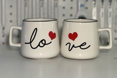 two coffee mugs with the words love painted on them