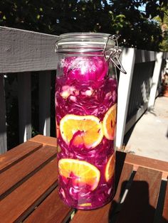 a jar filled with liquid sitting on top of a wooden table next to a fence