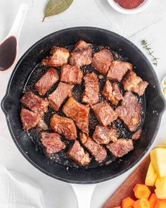 pork chops cooking in a skillet with carrots, potatoes and other ingredients