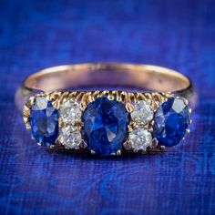 A stunning antique late Victorian ring modelled in 18ct gold and claw set with a trilogy of deep blue sapphires, with four old mine cut diamonds glistening in between. The largest sapphire is approx. 0.85ct in the centre, flanked by two 0.55ct stones on either side (approx. 2ct total). The diamonds are approx. 0.08ct each and have superb SI1 clarity - H colour.  The stones contrast and complement each other beautifully and look magnificent spread out across the finger.  We recommend you insure f Heirloom Blue Sapphire Ring With Rose Cut Diamonds, Classic Blue Diamond Ring With Single Cut, Antique Blue Rings With Brilliant Cut, Antique Blue Brilliant Cut Ring, Antique Blue Oval Diamond Ring, Classic Royal Blue Sapphire Ring, Antique Blue Diamond Rings, Antique Blue Diamond Ring For Formal Occasions, Antique Blue Diamond Ring With Rose Cut