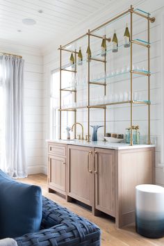 a living room filled with furniture and a large open book shelf above a kitchen sink