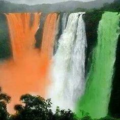 the rainbow colored water is flowing down the side of a waterfall, with trees around it