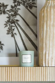 a candle sitting on top of a wooden shelf next to a palm tree wallpaper