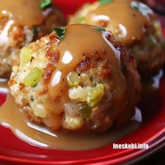 two meatballs covered in gravy on a red plate