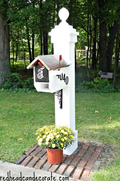 a mailbox in the shape of a cross with two letters on it and a potted plant next to it