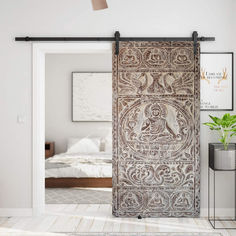 an ornate wooden door is opened to reveal a bedroom with white walls and wood floors