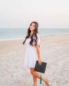 a woman is walking on the beach with her hand in her pocket and holding a black purse