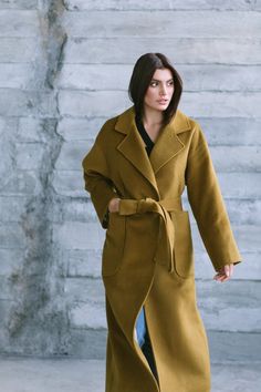 Introducing our loose-fitting mustard-colored wrap wool coat, designed for both lightness and comfort. The H-shaped silhouette offers versatility and suits different body types, ensuring a flattering look. With two practical patch pockets, this coat effortlessly combines functionality and style, allowing you to keep your essentials within easy reach. The lowered shoulders add a relaxed and contemporary touch. The belt accentuates the waist, creating an attractive and feminine silhouette. Crafted Mustard Oversized Outerwear For Spring, Chic Mustard Outerwear For Work, Yellow Wool Outerwear For Winter, Yellow Long Coat For Fall, Chic Oversized Yellow Outerwear, Chic Yellow Oversized Outerwear, Elegant Yellow Winter Outerwear, Chic Mustard Outerwear For Fall, Mustard Coat