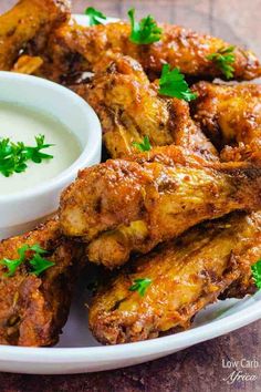 chicken wings with ranch dressing on a white plate and garnished with parsley