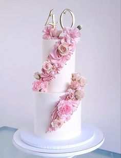 a three tiered white cake with pink flowers on top and the number forty written in gold