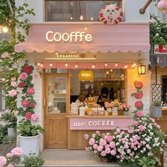 the outside of a coffee shop with pink flowers