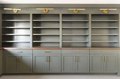 an empty room with many gray cabinets and gold pulls on the doors is pictured in this image