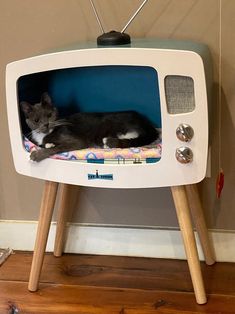 a black and white cat laying on top of an old tv with the screen turned off