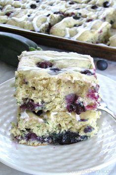 a close up of a piece of cake on a plate near a pan of blueberries