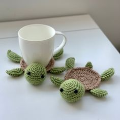 two crocheted sea turtle coasters and a coffee cup on a white table