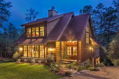 a large house with lots of windows and lights on it's front porch at night