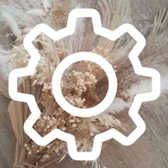 an image of a cog wheel with dried flowers in it on a wooden surface