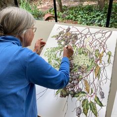 an older woman is painting in the woods