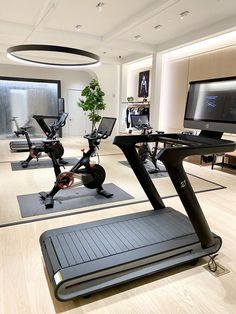 an exercise room with treadmills and television